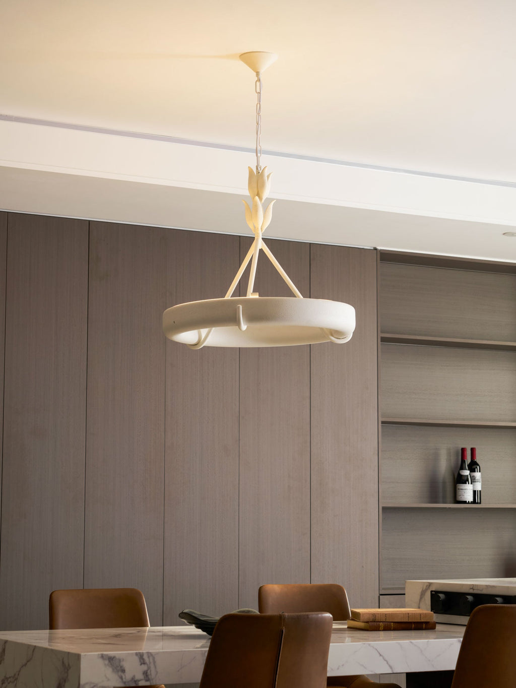 Three-quarter view of the white ring with open shelves and a wine bottle behind it; a Clérachic chandelier.