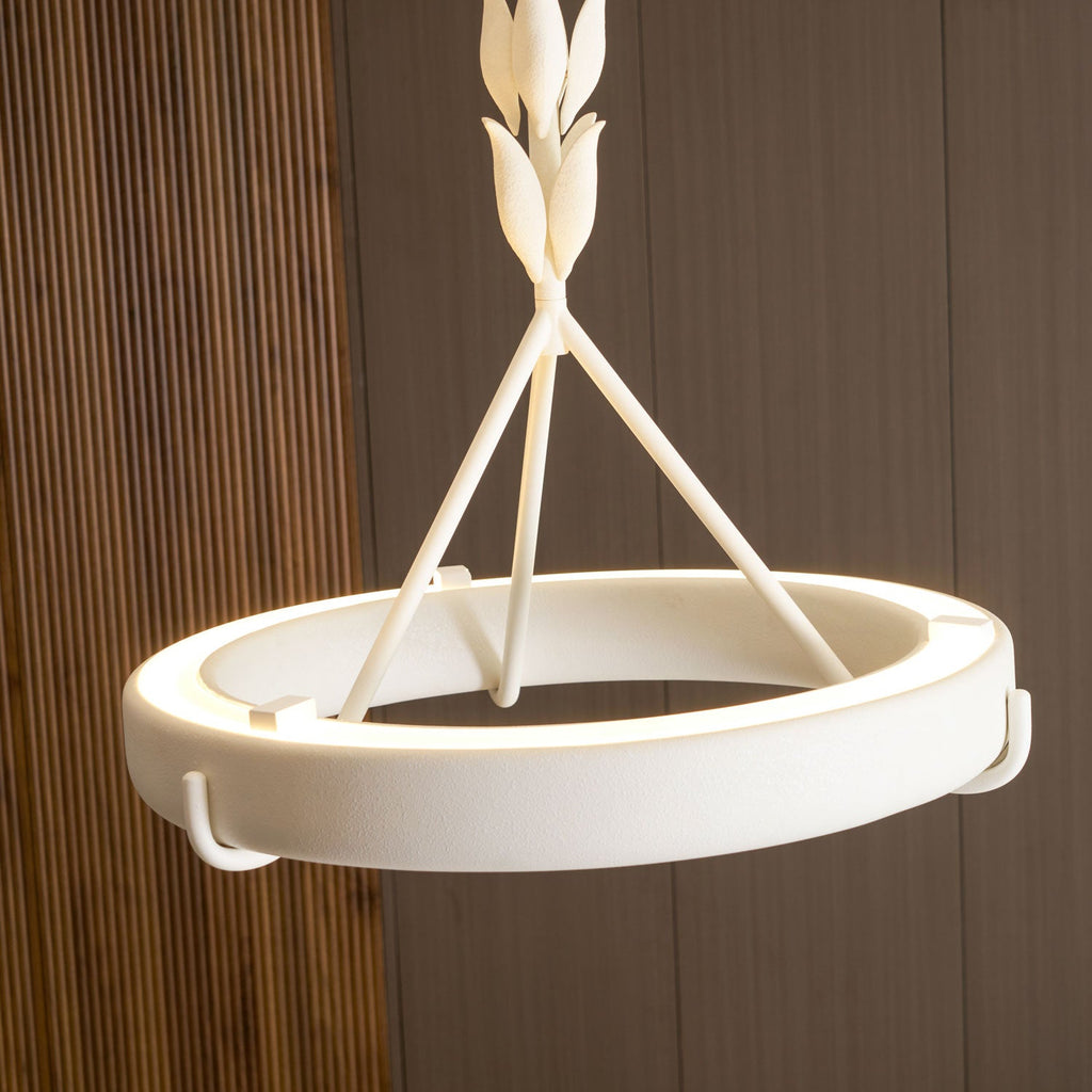 Lit ring with a bright light strip along its inner edge and the leaf-bud stem above, on a walnut wall; a Clérachic chandelier.
