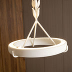 Lit ring with a bright light strip along its inner edge and the leaf-bud stem above, on a walnut wall; a Clérachic chandelier.