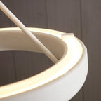Close view of the glowing light strip inside the white ring, where a rod meets its edge on this Clérachic chandelier.