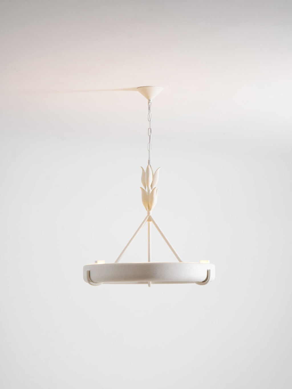 This Clérachic chandelier hangs on a chain on a soft grey studio backdrop, seen from below with its hooks and a leaf-bud stem.
