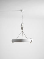 Straight-on studio shot of the white ring on its chain, with the leaf buds and three rods above; a Clérachic chandelier.