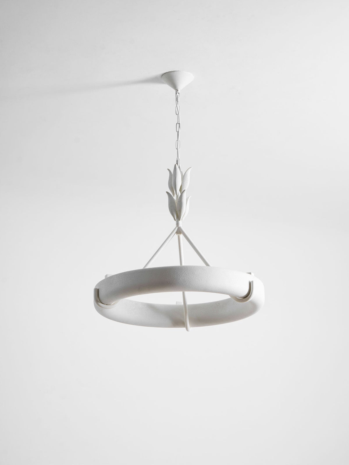 Tilted studio view of the white ring showing its curved rim and one hook, against pale grey; a Clérachic chandelier.