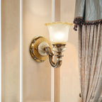 Lit single-head Clérachic wall light on a warm cream wall, beside a draped curtain with a beaded trim.