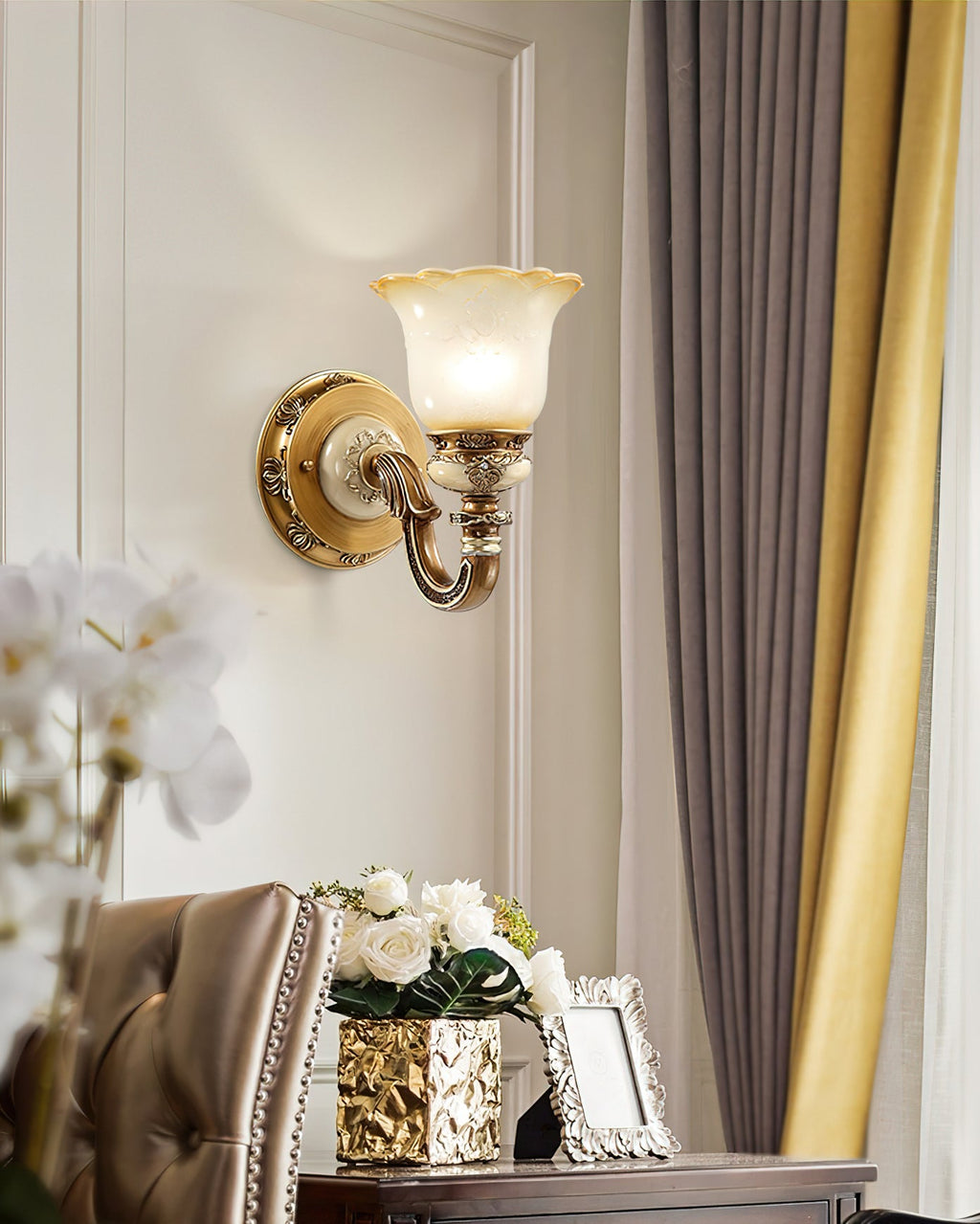 Single-head Clérachic wall light on a white wall, set between white orchid blooms and a gold-tinted vase of roses.