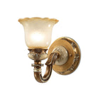 Single-head Clérachic wall light on a white backdrop, its bell-shaped glass shade glowing above a detailed bronze and gold arm.