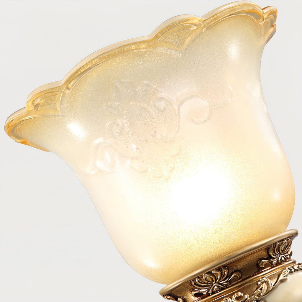 Close view of the scalloped, patterned glass shade on this Clérachic wall light, glowing warm above its carved base.