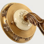 Close view of the round backplate on this Clérachic wall light, with embossed petal detail and a cream ceramic-look centre.