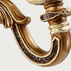 Close view of the curved arm on this Clérachic wall light, with dark textured inlay, gold edging and a patterned collar.