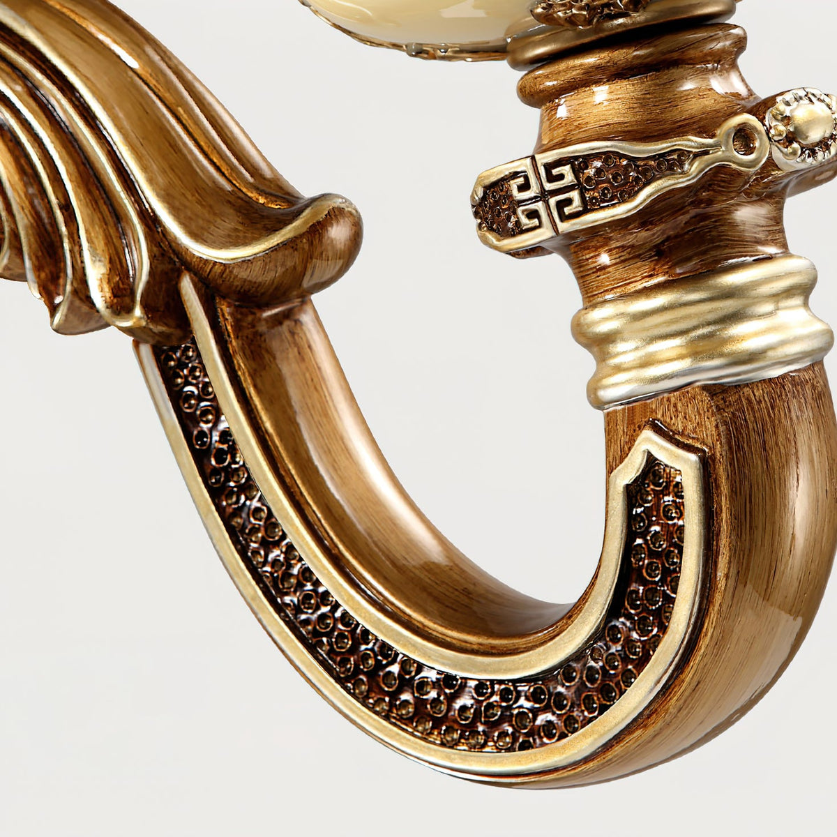 Close view of the curved arm on this Clérachic wall light, with dark textured inlay, gold edging and a patterned collar.