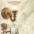 Single-head Clérachic wall light in the foreground, with a blurred garden of pink blossom and a wooden chair behind it.