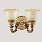 Double-head Clérachic wall light on a pale grey backdrop, two frosted shades above carved gold arms and a round backplate.