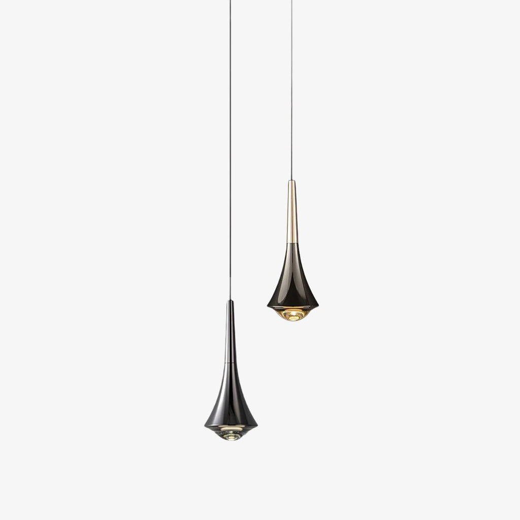 Two Clérachic pendants on thin cords, one in dark chrome with a flared body and one with a pale metal neck, on a plain backdrop.