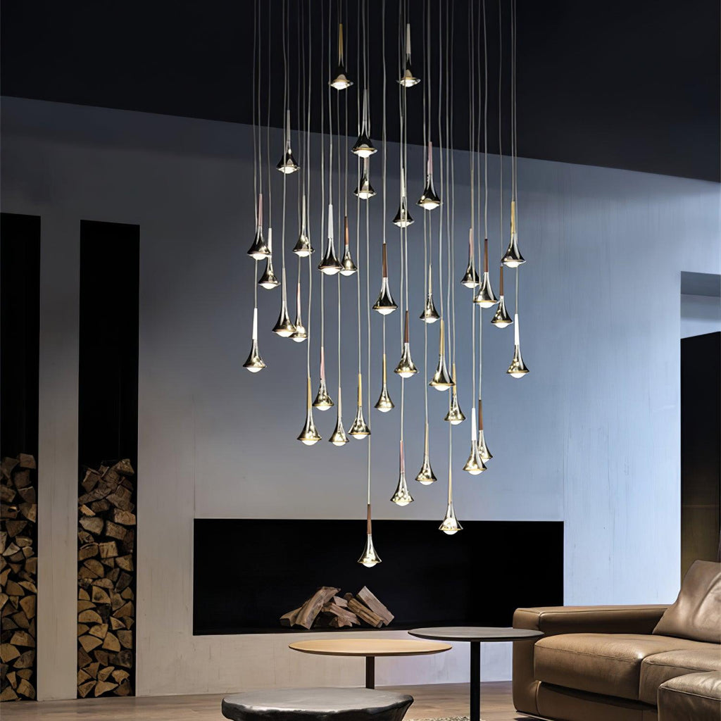 Many Clérachic chrome drops hang at staggered heights in a tall room with a firewood niche and a leather sofa.