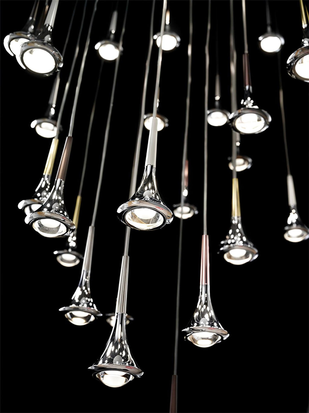 Close view of polished Clérachic drop pendants at varied heights, each with a round bulb in its flared base, on black.