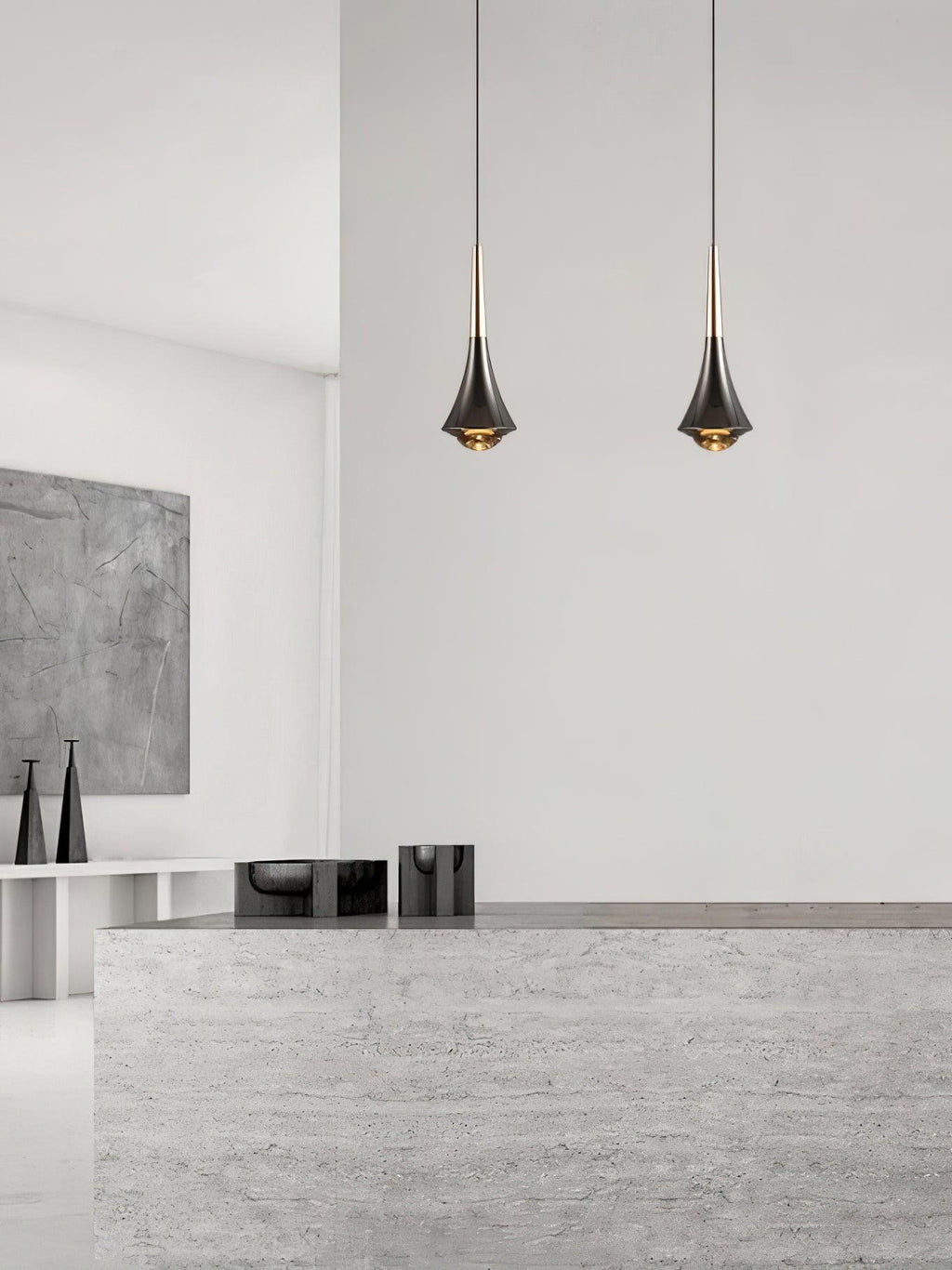 Two Clérachic pendants with tapered dark bodies hang side by side in front of a pale stone counter and white wall.