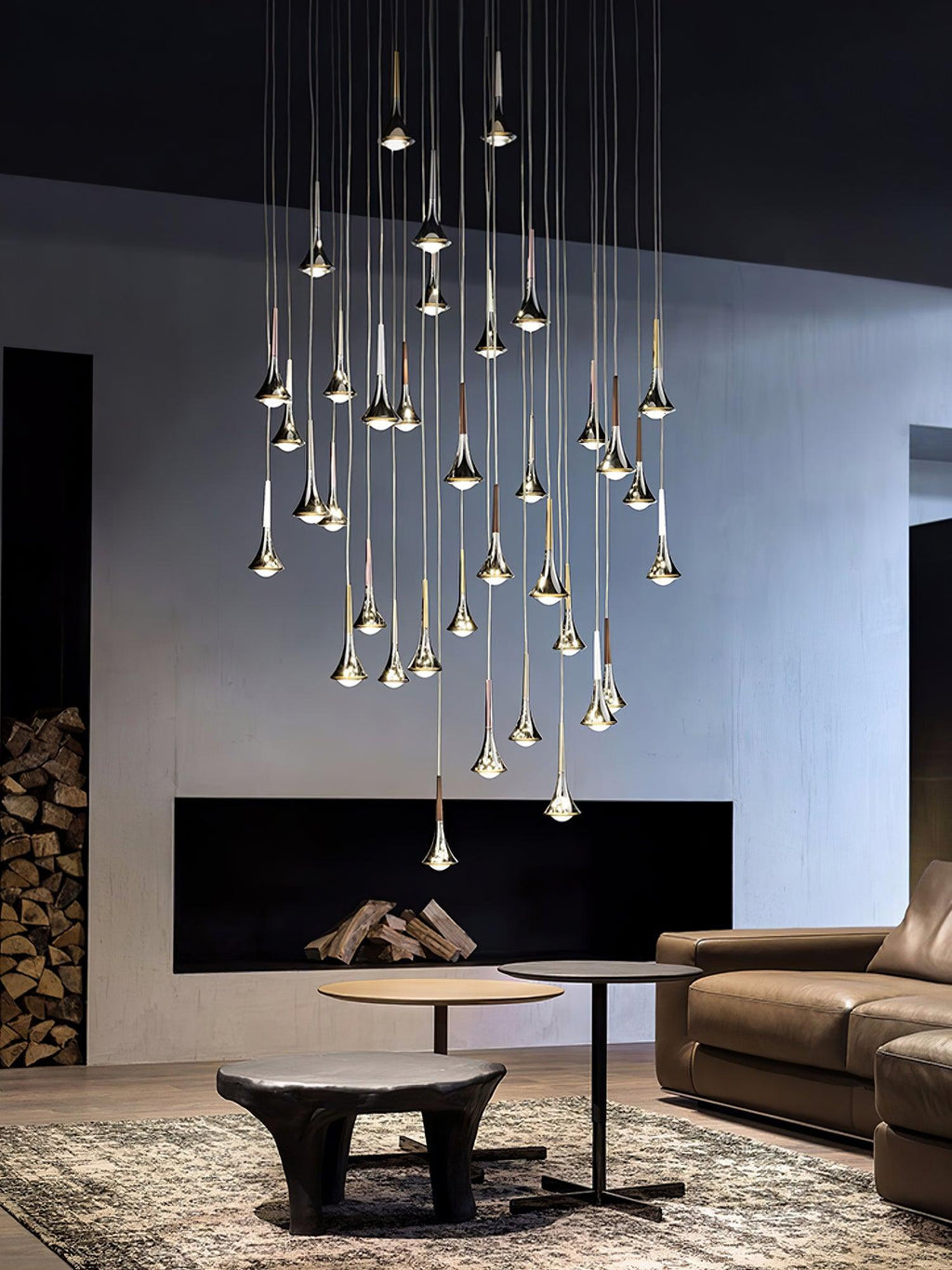 Wider view of a tall cluster of Clérachic chrome drops hanging in a lounge with a leather sofa and a patterned rug.