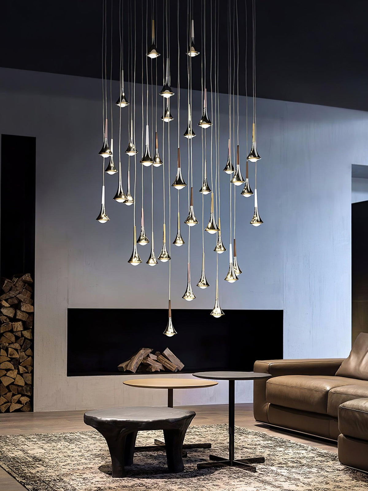 Wider view of a tall cluster of Clérachic chrome drops hanging in a lounge with a leather sofa and a patterned rug.