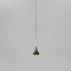 A Clérachic pendant with a flared dark chrome body and a pale champagne neck, on a thin cord against light grey.