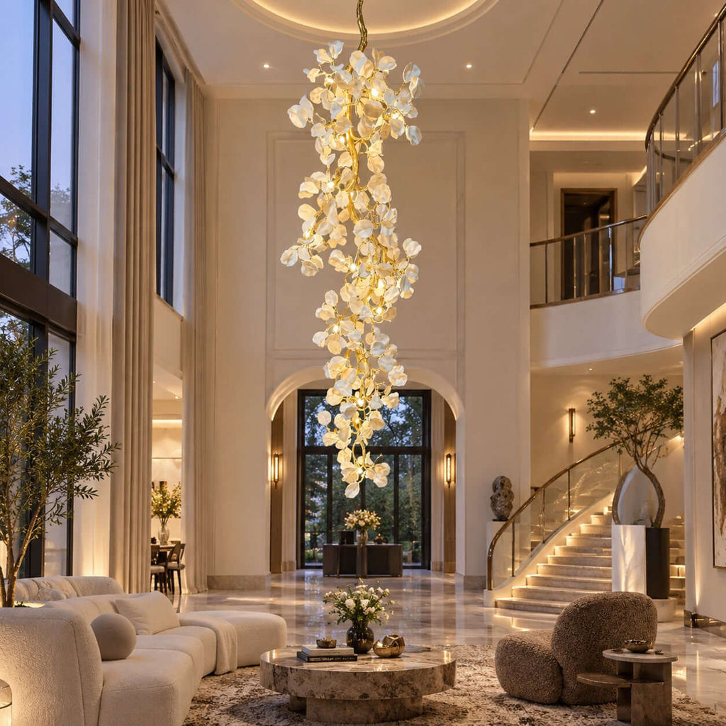 This Clérachic cascading petal chandelier drops through a double-height hall, above a cream sofa and a curved staircase.