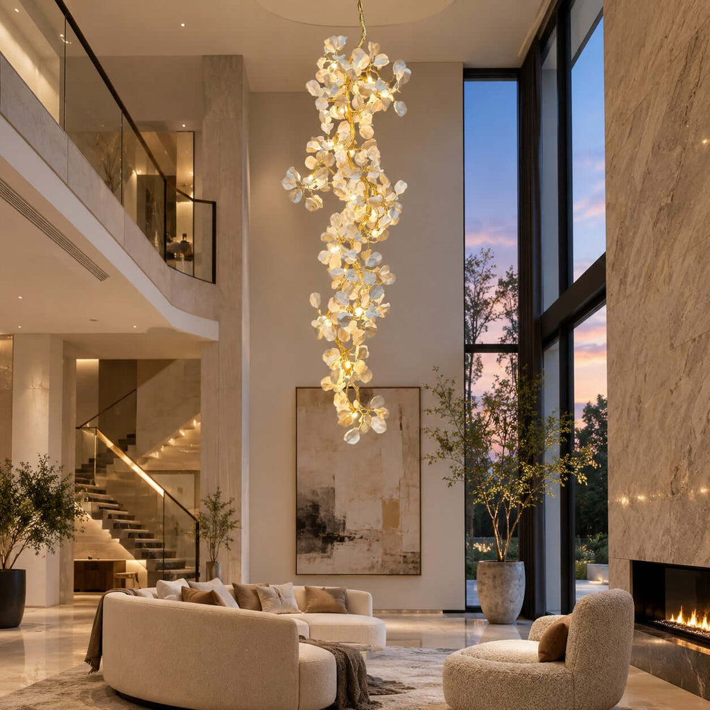 The Clérachic cascading chandelier beside tall windows at dusk, above a staircase and a cream sofa with a large abstract artwork.