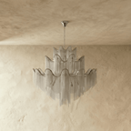 Clérachic silver chain-fringe chandelier switched off, showing the wavy ribbon rims and candle-style arms inside the tiers.