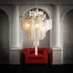 Clérachic chain-fringe chandelier lit above a red leather armchair in a room with pale classical columns and arches.