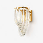 A Clérachic wall light with cascading clear glass strands looped over a gold backplate, on a plain white backdrop.