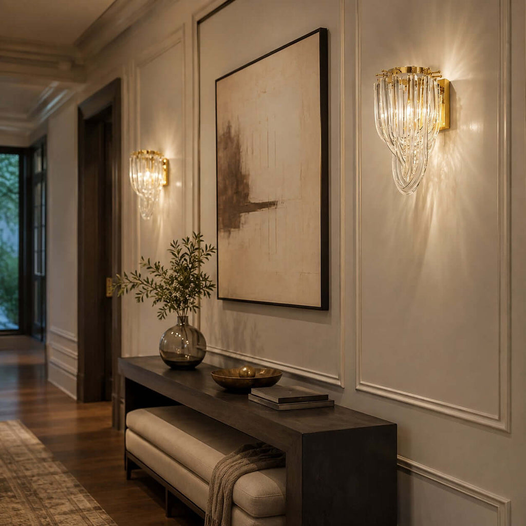 Warm light spills from this Clérachic wall light, with its looped glass strands and gold backplate, beside a large abstract canvas.