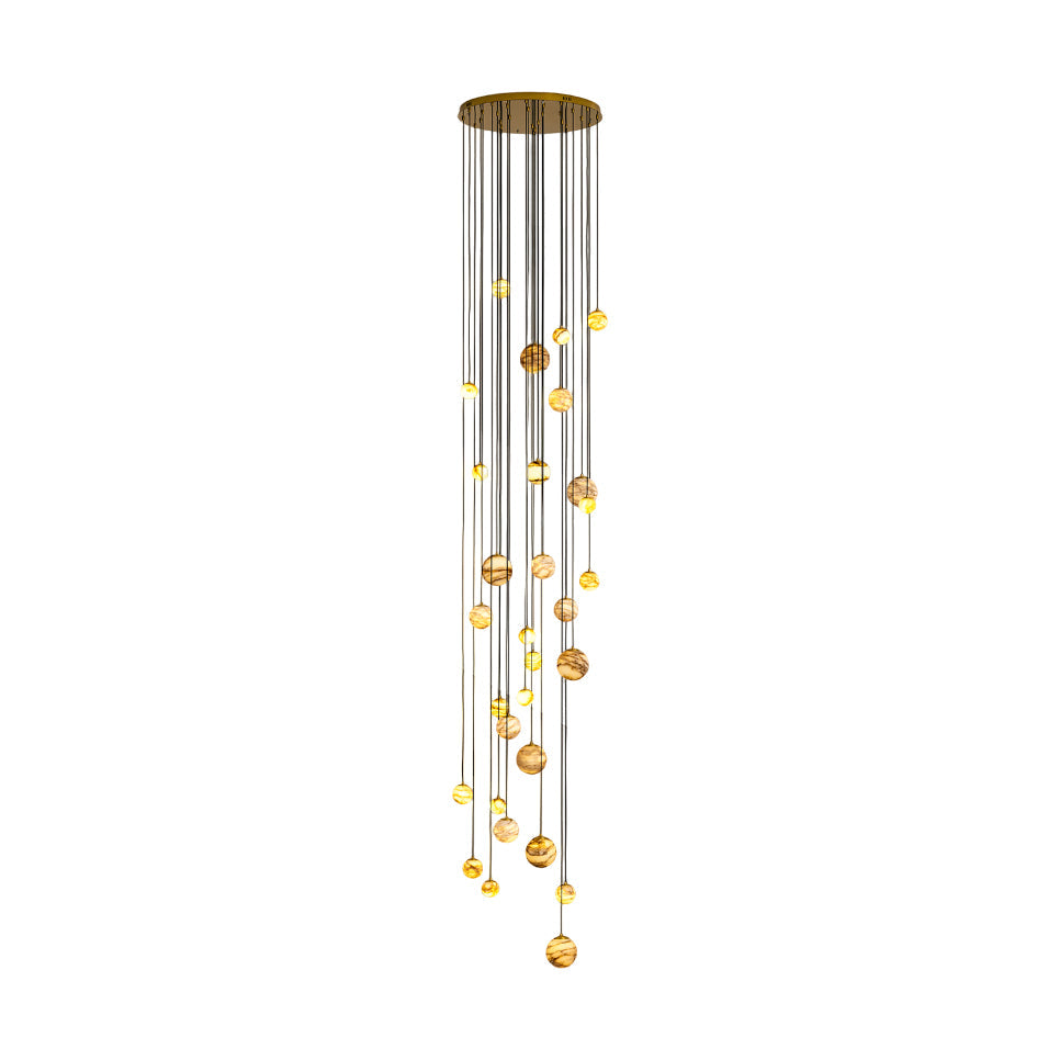 The Clérachic Cascading Globe Chandelier with the polished gold canopy, lit alabaster spheres dropping in a long spiral on black cords.