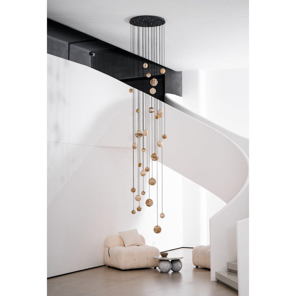 The Clérachic Cascading Globe Chandelier hung in a curved stairwell void, its alabaster spheres falling past a white spiral stair by day.