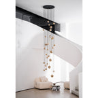 The Clérachic Cascading Globe Chandelier hung in a curved stairwell void, its alabaster spheres falling past a white spiral stair by day.
