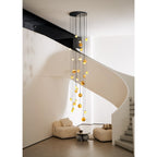Lit at dusk, the Clérachic Cascading Globe Chandelier warms a two-storey stairwell, each sphere glowing honey-amber above the seating.