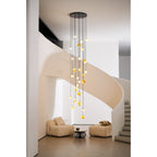 Framed by the stair curve, the Clérachic Cascading Globe Chandelier drops its glowing alabaster spheres to head height above a low table.