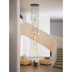 The Clérachic Cascading Globe Chandelier viewed past a white pillar, the cascade of lit spheres reading as one column of warm light.