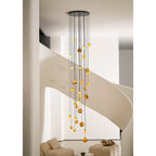 The Clérachic Cascading Globe Chandelier lit against a pale stairwell wall, staggered drops turning a group of pendants into a cascade.