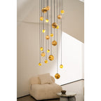 Close view of the Clérachic Cascading Globe Chandelier's lower spheres, lit alabaster showing amber banding above a bouclé armchair.