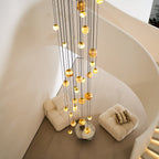 Seen from the landing above, the Clérachic Cascading Globe Chandelier's cords drop past the stair curve to the seating on the floor below.
