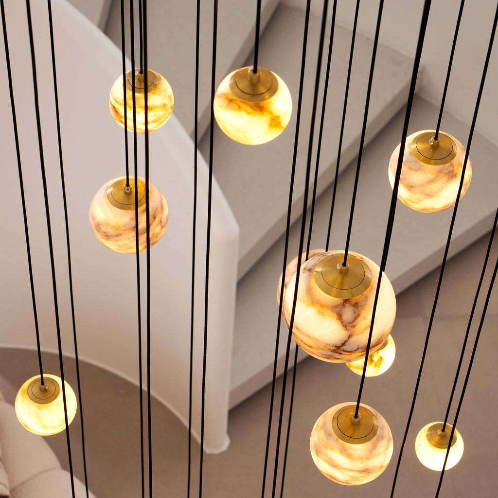 Detail of the Clérachic Cascading Globe Chandelier: brushed brass caps sit over each alabaster sphere where the black flex meets the stone.