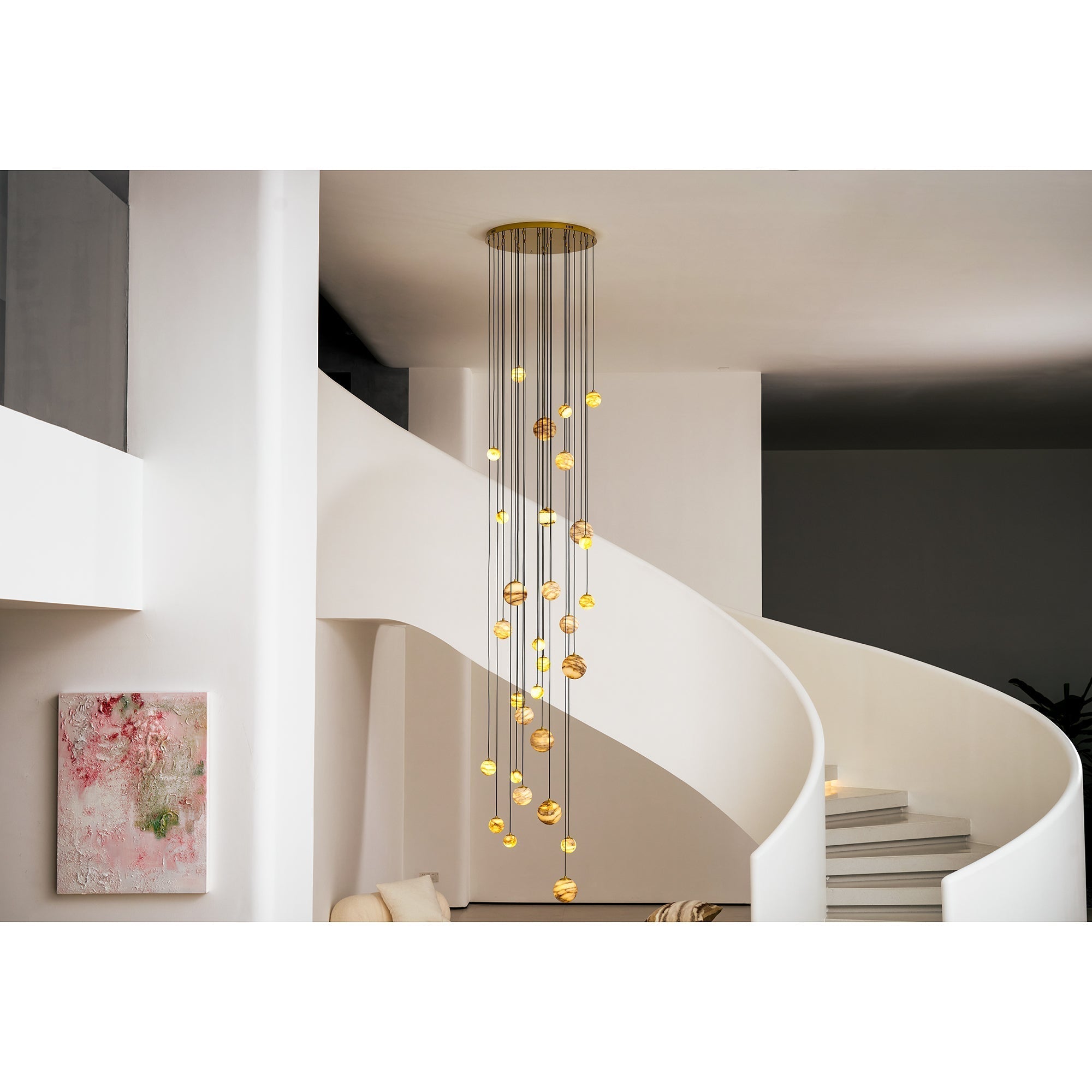 Room view of the Clérachic Cascading Globe Chandelier filling the double-height space between a spiral stair and a framed canvas.
