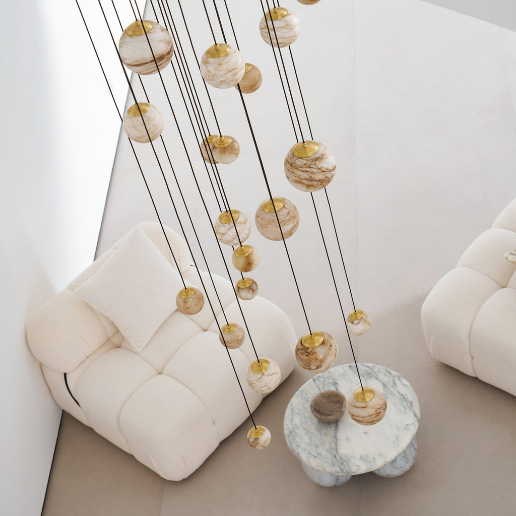 Unlit by day, the Clérachic Cascading Globe Chandelier spheres read warm off-white, banding shifting from one quarried stone to the next.