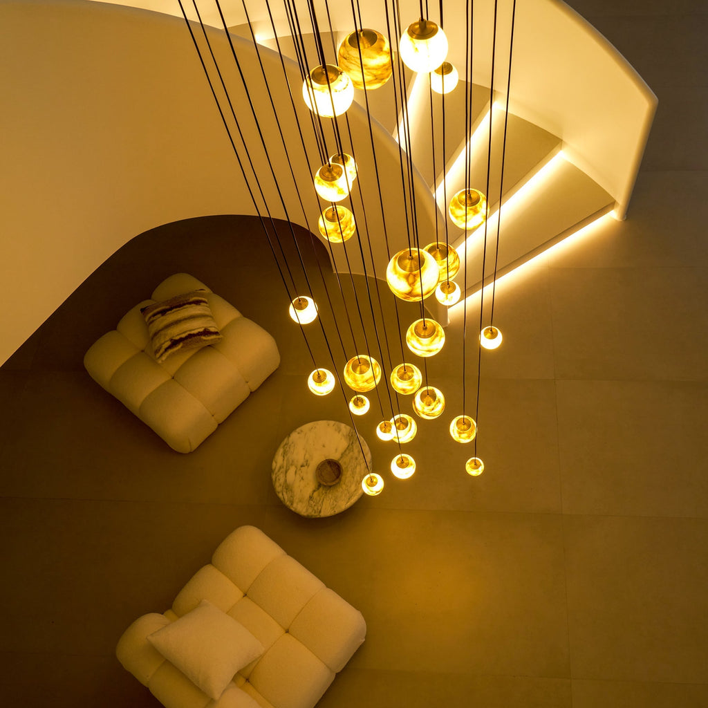 Night view from above of the Clérachic Cascading Globe Chandelier, warm pools of light falling across the floor and the seating below.