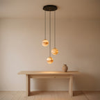The three-head configuration above an oak console in an entrance hall, three lit alabaster spheres staggered beneath the matte black canopy