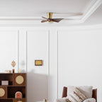 A small Clérachic ceiling fan in gold and walnut sits high on a white ceiling, above panelled walls and a wooden cabinet with cane doors.
