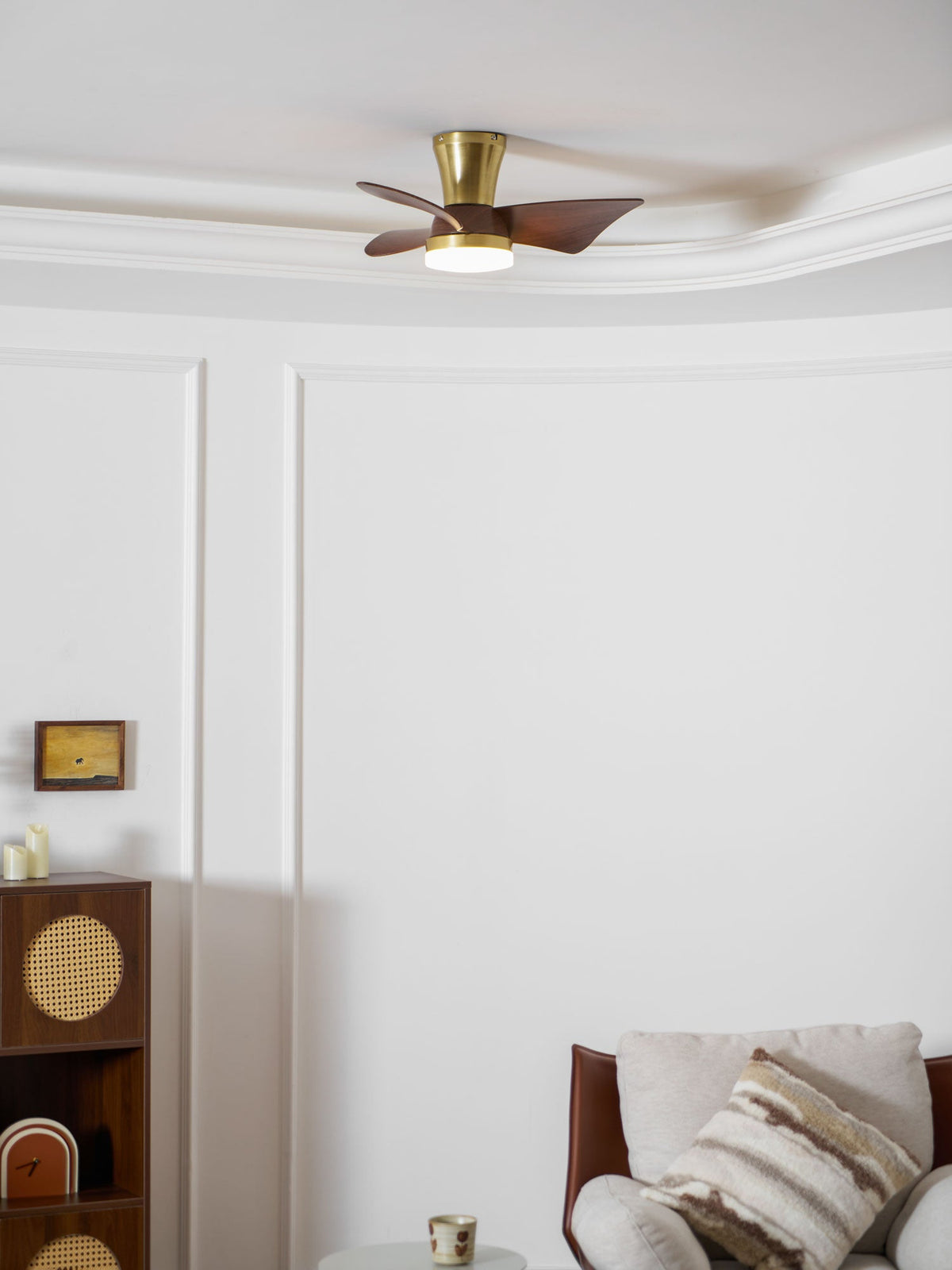 Seen from below, this Clérachic ceiling fan sits on a curved ceiling edge, with a cane-fronted cabinet and a leather armchair in the corner.