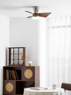 The Clérachic nickel ceiling fan above a corner with a bookcase, a small display cabinet and a round table with a white cloth.