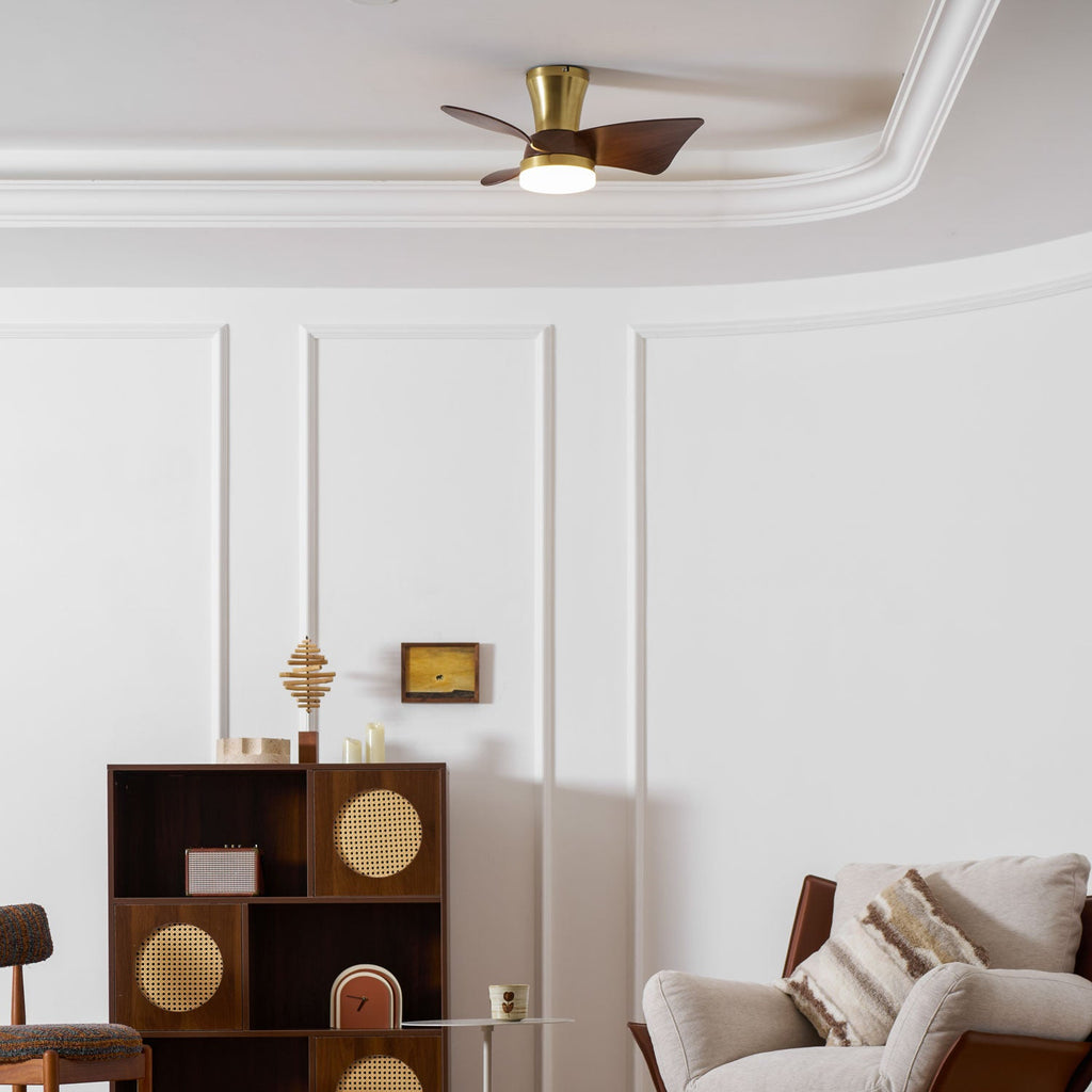 The Clérachic gold and walnut ceiling fan close to the ceiling, above a panelled wall, a cane-fronted shelf and a leather-and-linen armchair.