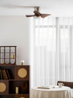 A Clérachic nickel ceiling fan above a tall display cabinet, a bookshelf and a table with a teacup, with light curtains at the window.