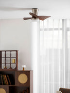 Looking up at the Clérachic nickel ceiling fan, with a lit globe light, over a bookshelf, a cane cabinet and a round table with a cloth.