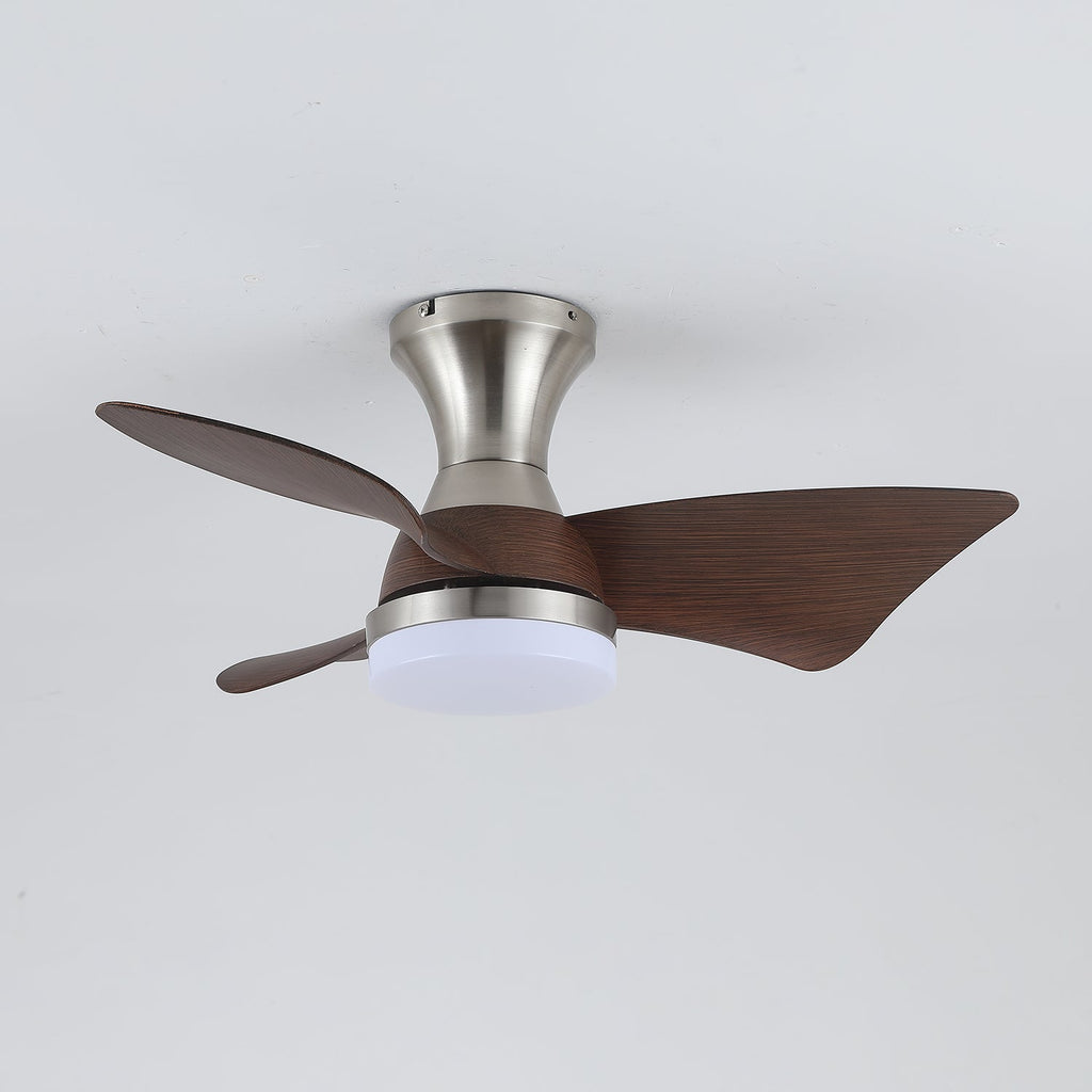 A Clérachic nickel ceiling fan with a cool white light on, showing its three dark walnut-grain blades against a pale grey ceiling.
